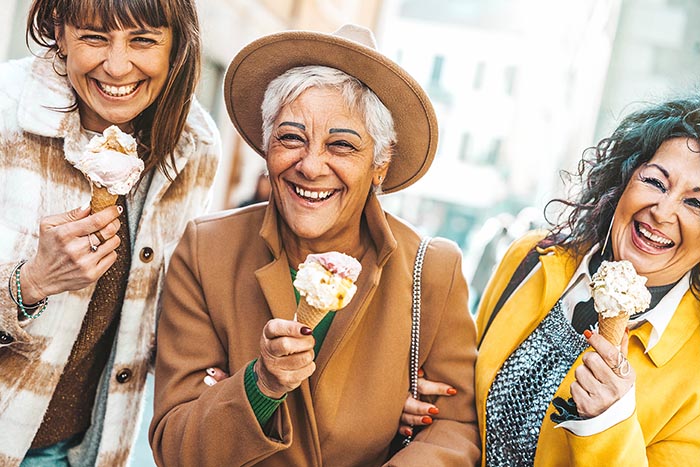 Three mature women eating ice cream cone outside - Older female