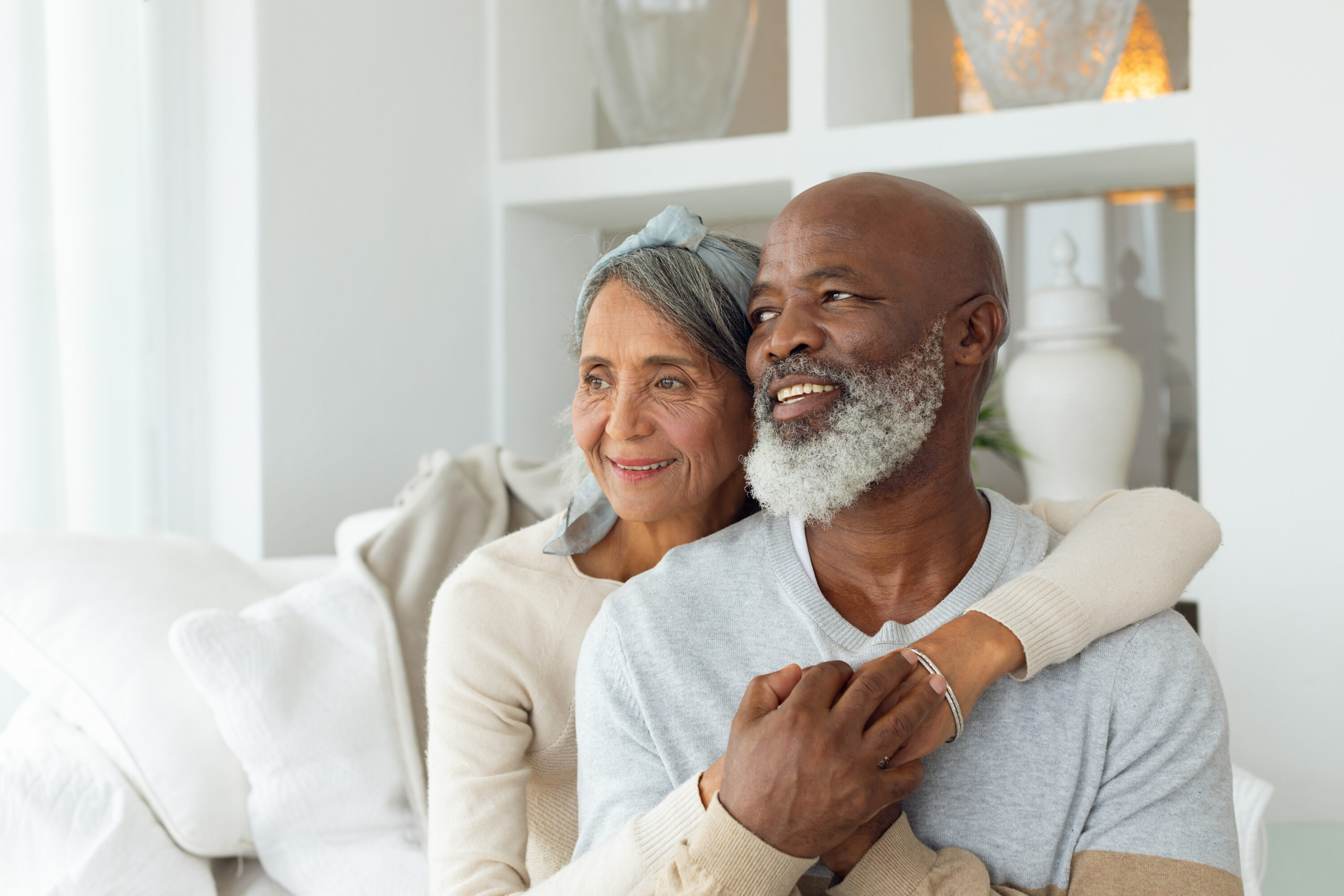 Senior couple smiling and embracing on sofa