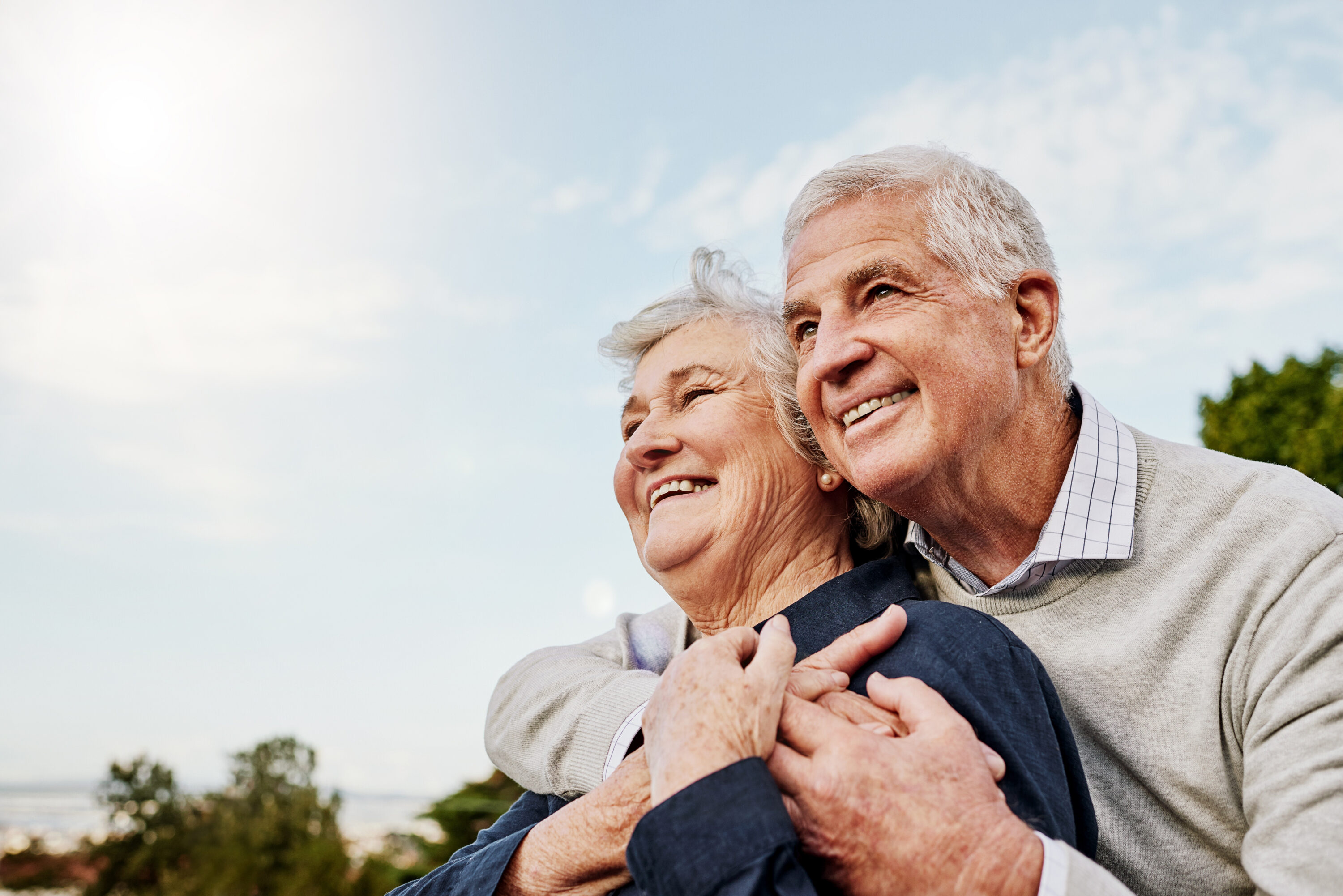 Smiling elderly couple embracing outdoors at sunset