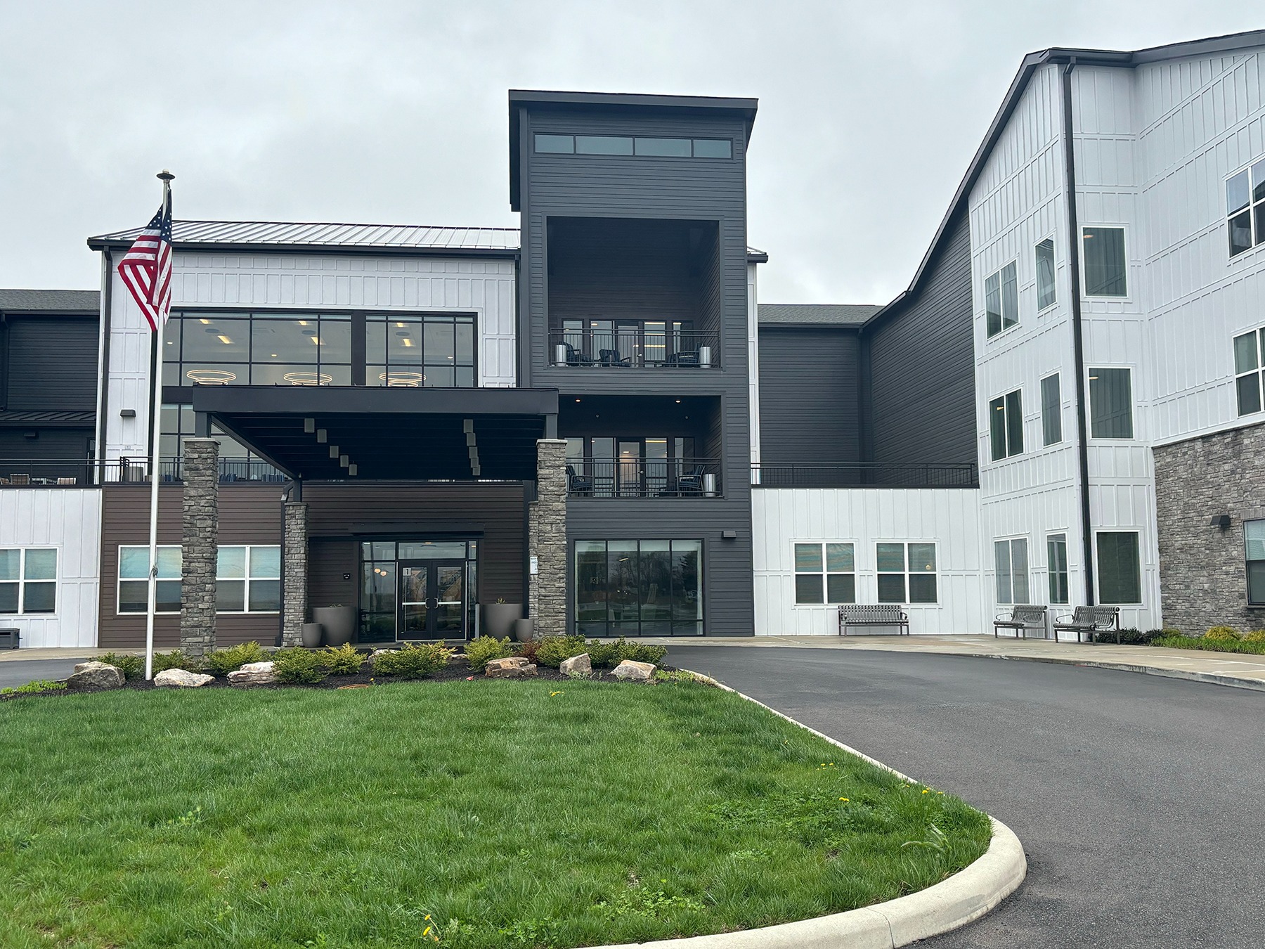 Modern apartment building with covered entrance and flag