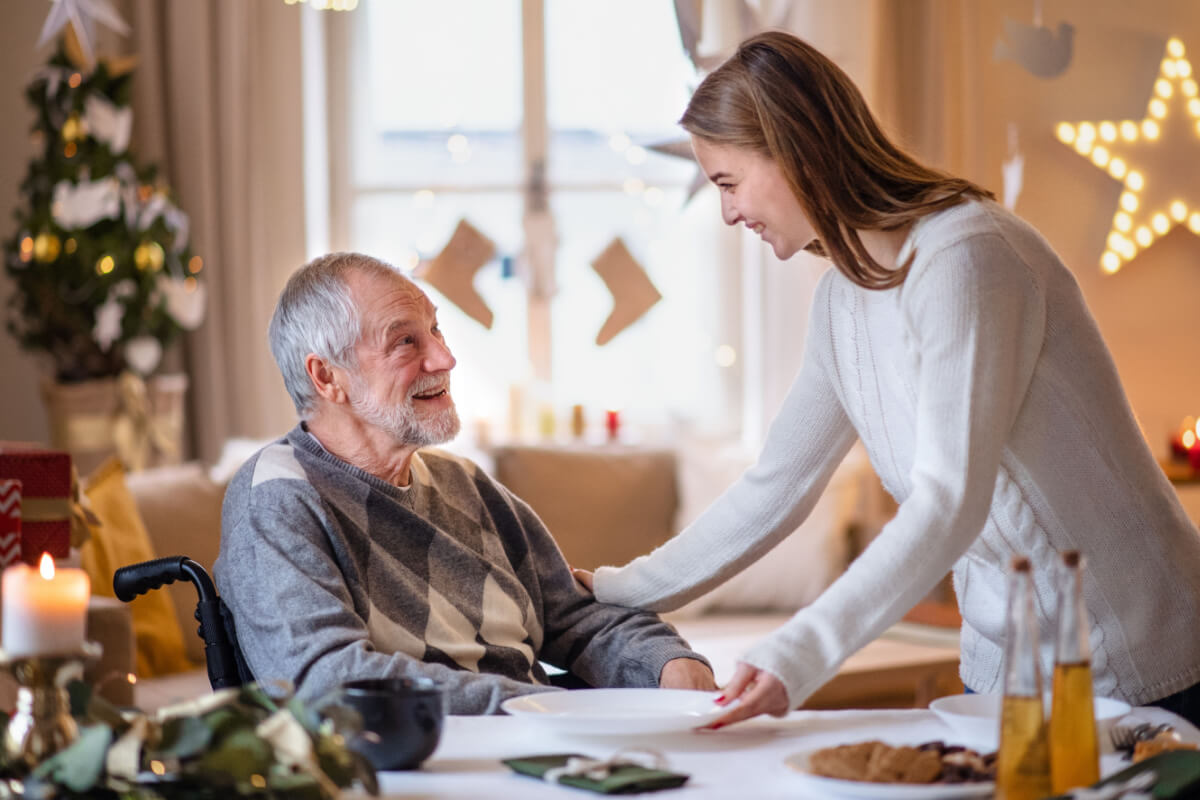 Young woman serving elderly man at holiday dinner