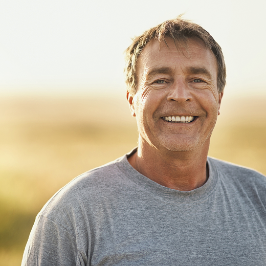 Smiling middle-aged man in sunlit field