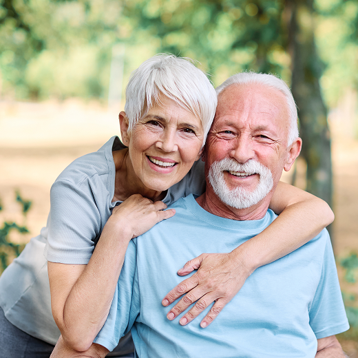 Smiling elderly couple embracing outdoors in park