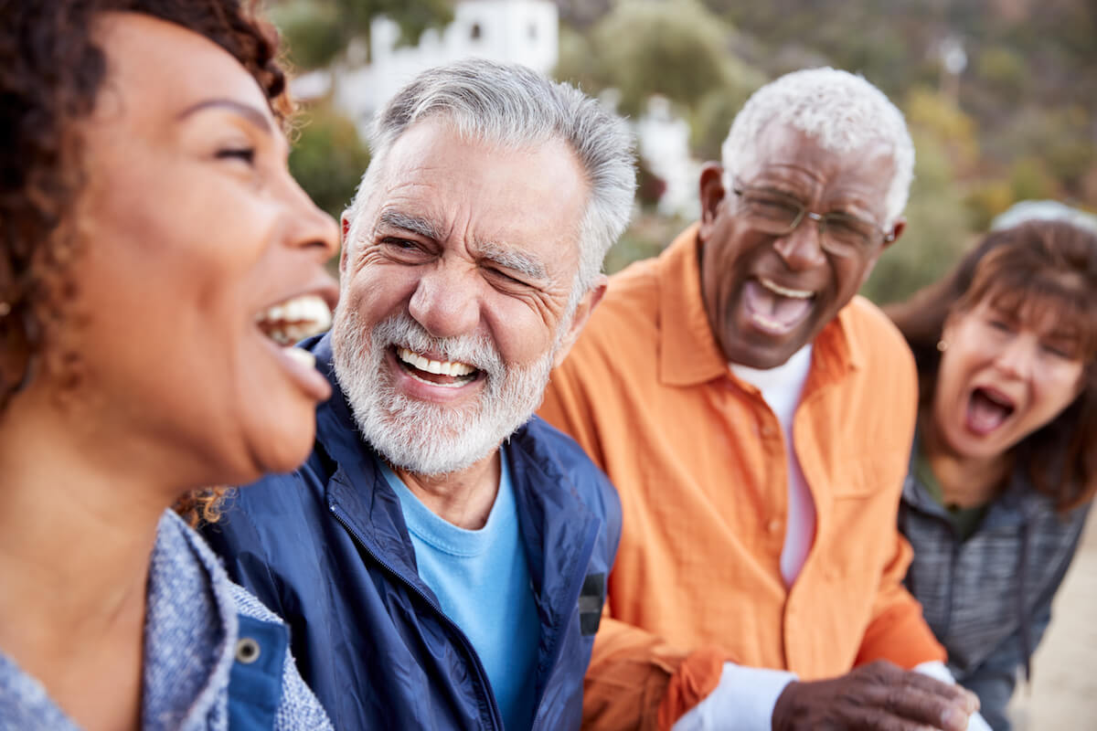 Four older adults laughing together outdoors