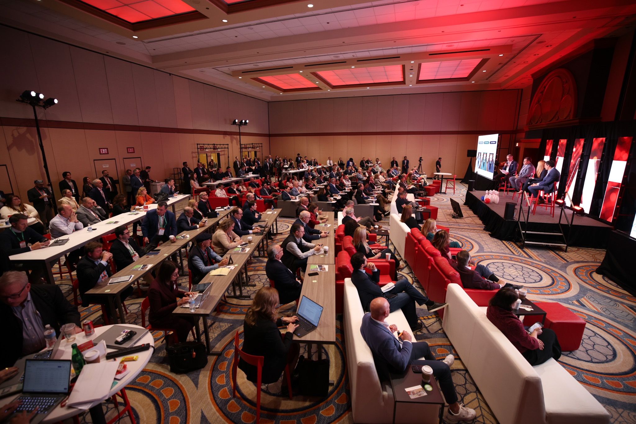 Audience attends panel discussion in red-lit conference ballroom