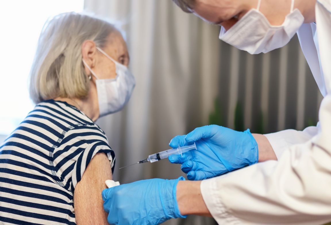 Healthcare worker administering vaccine to elderly woman
