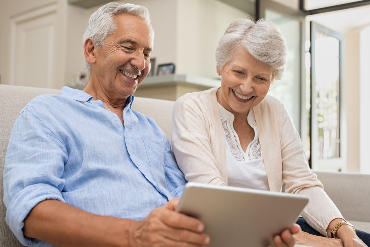Smiling senior couple using tablet on couch