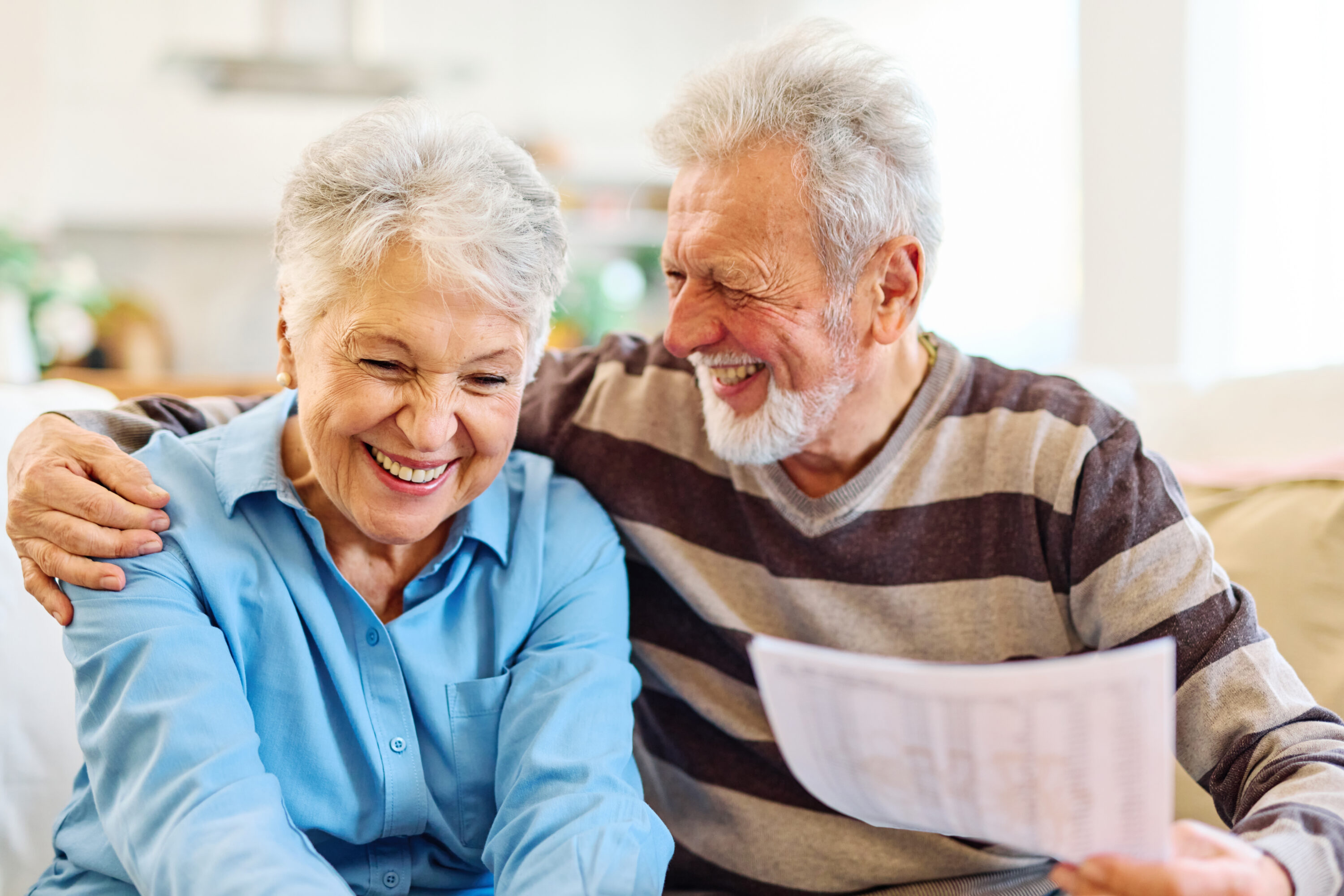Elderly couple smiling while reading document together
