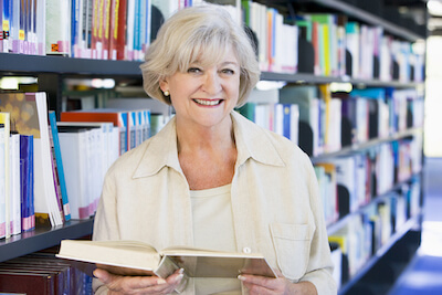 Smiling older woman holding book in library