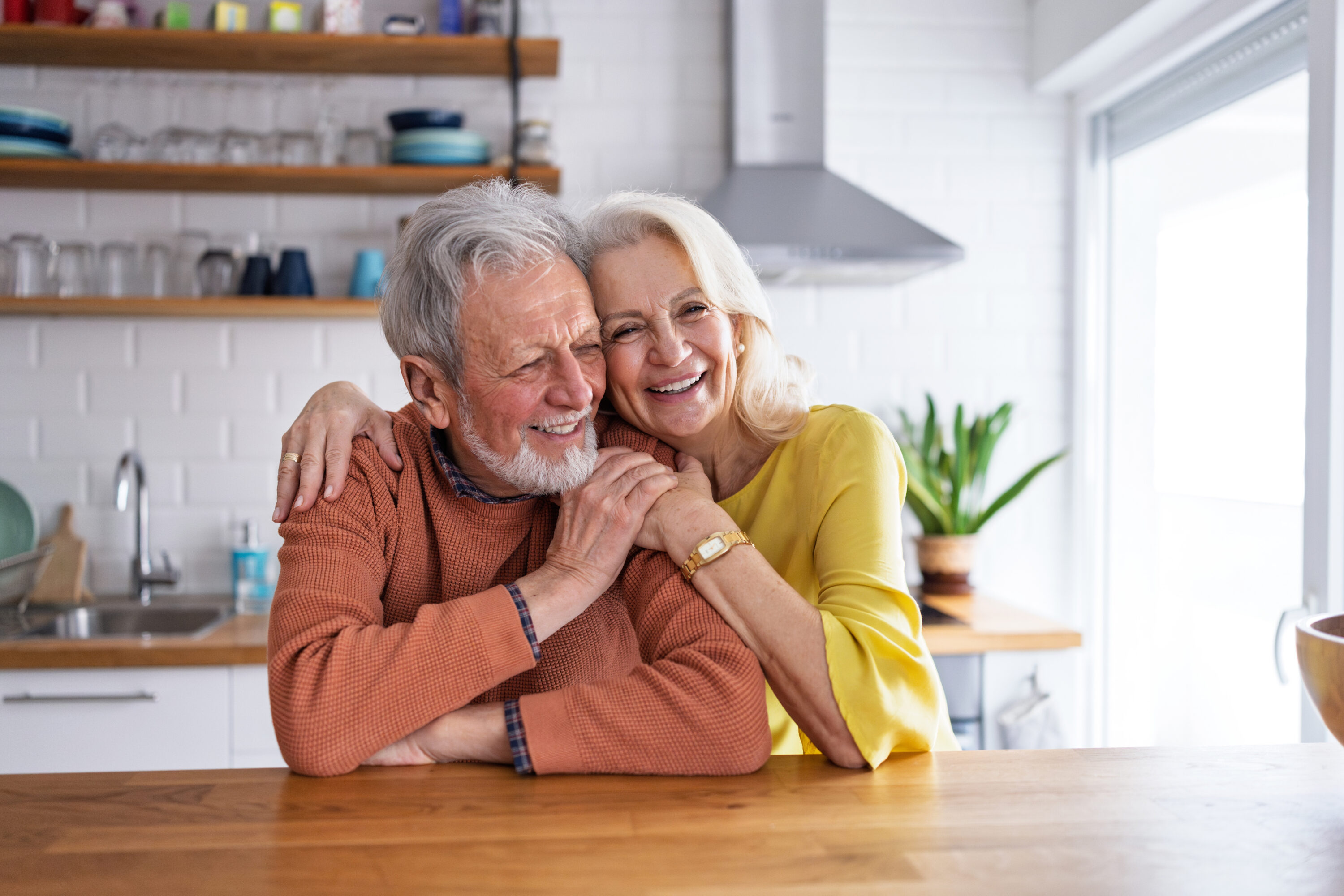 Smiling senior couple embracing in bright kitchen