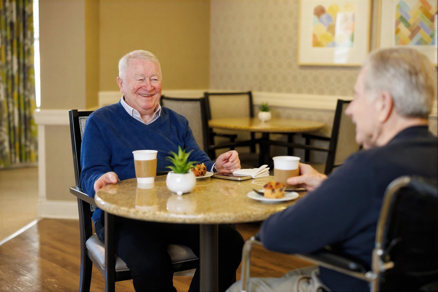 Two elderly men chatting over coffee indoors