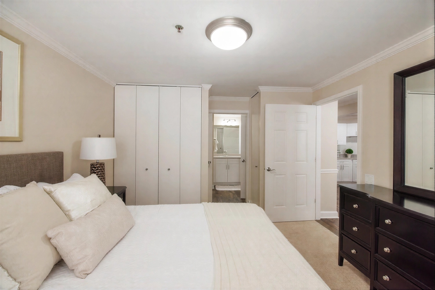 Neutral bedroom with dresser and open bathroom door