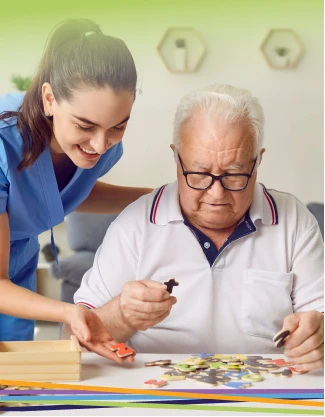 Caregiver assisting elderly man with puzzle
