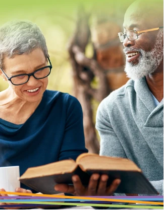Older couple smiling while reading a book outdoors