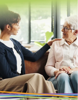 Woman comforting elderly woman on couch