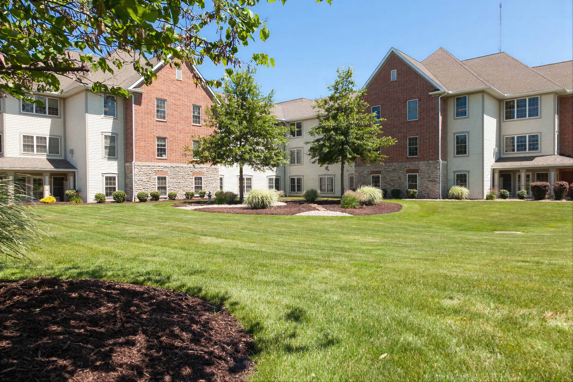 Brick apartment building with landscaped green lawn