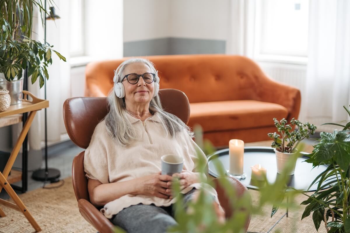 Senior woman relaxing with headphones and coffee
