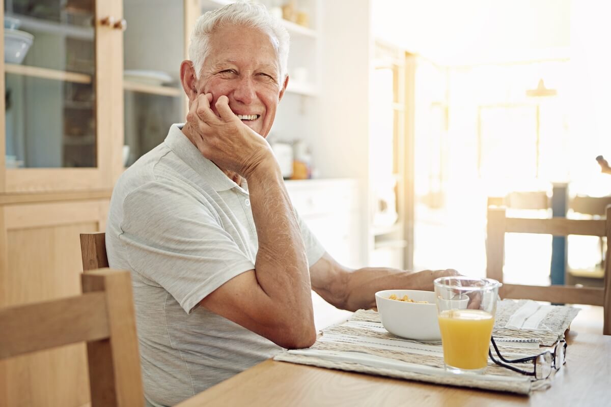 Smiling senior man eating breakfast at table