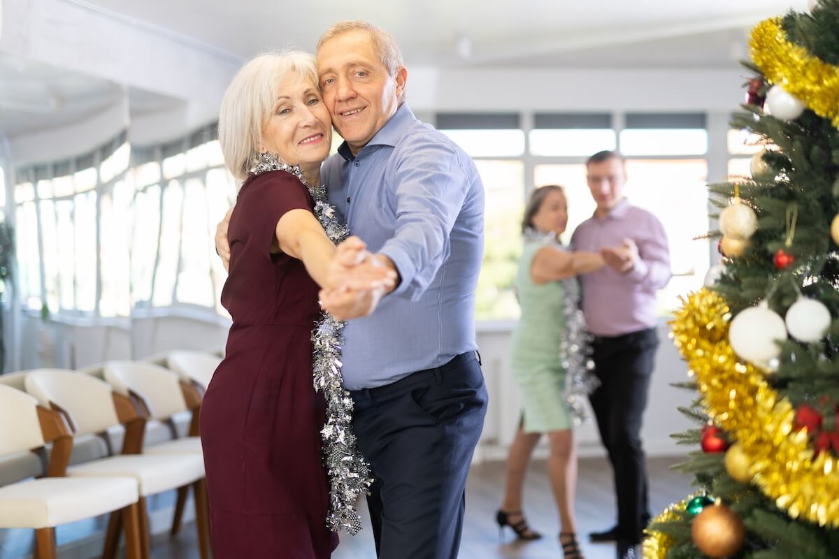 Senior couples dancing near decorated Christmas tree