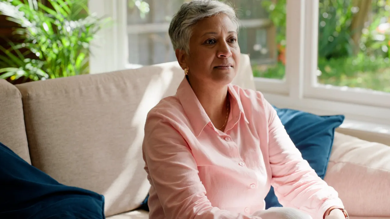 Middle-aged woman sitting on couch in sunlight