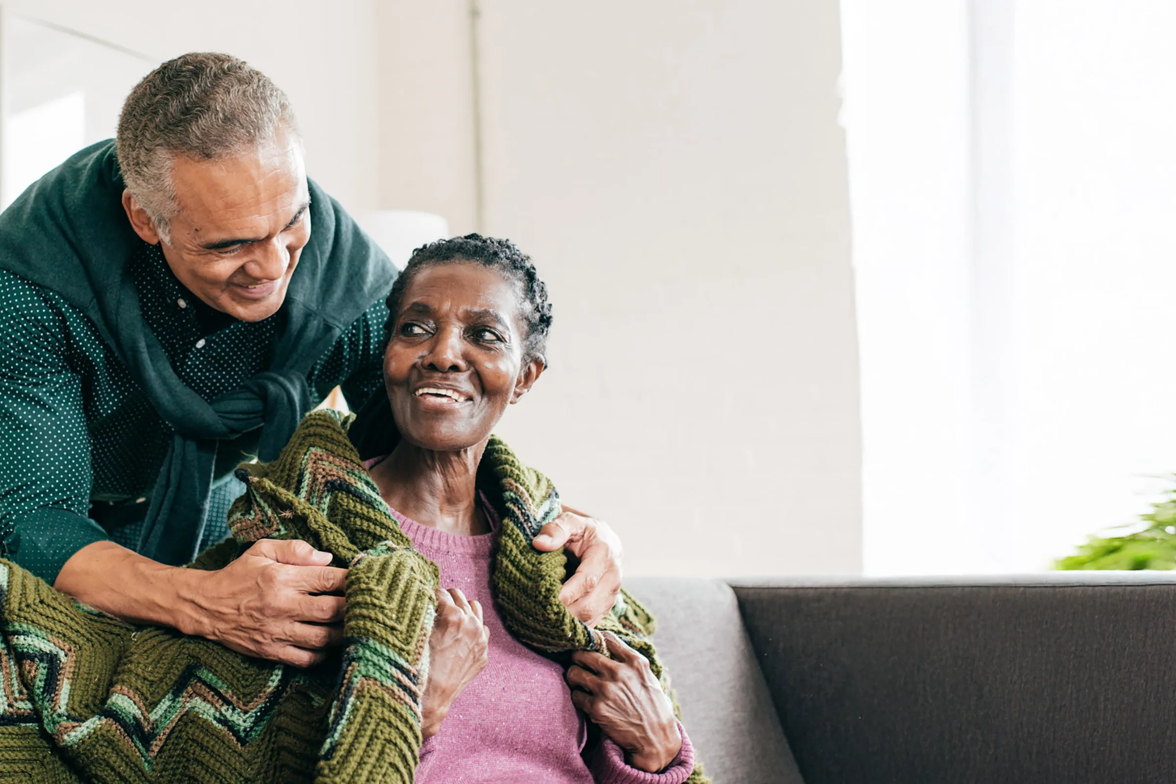 Man wrapping sweater around smiling older woman