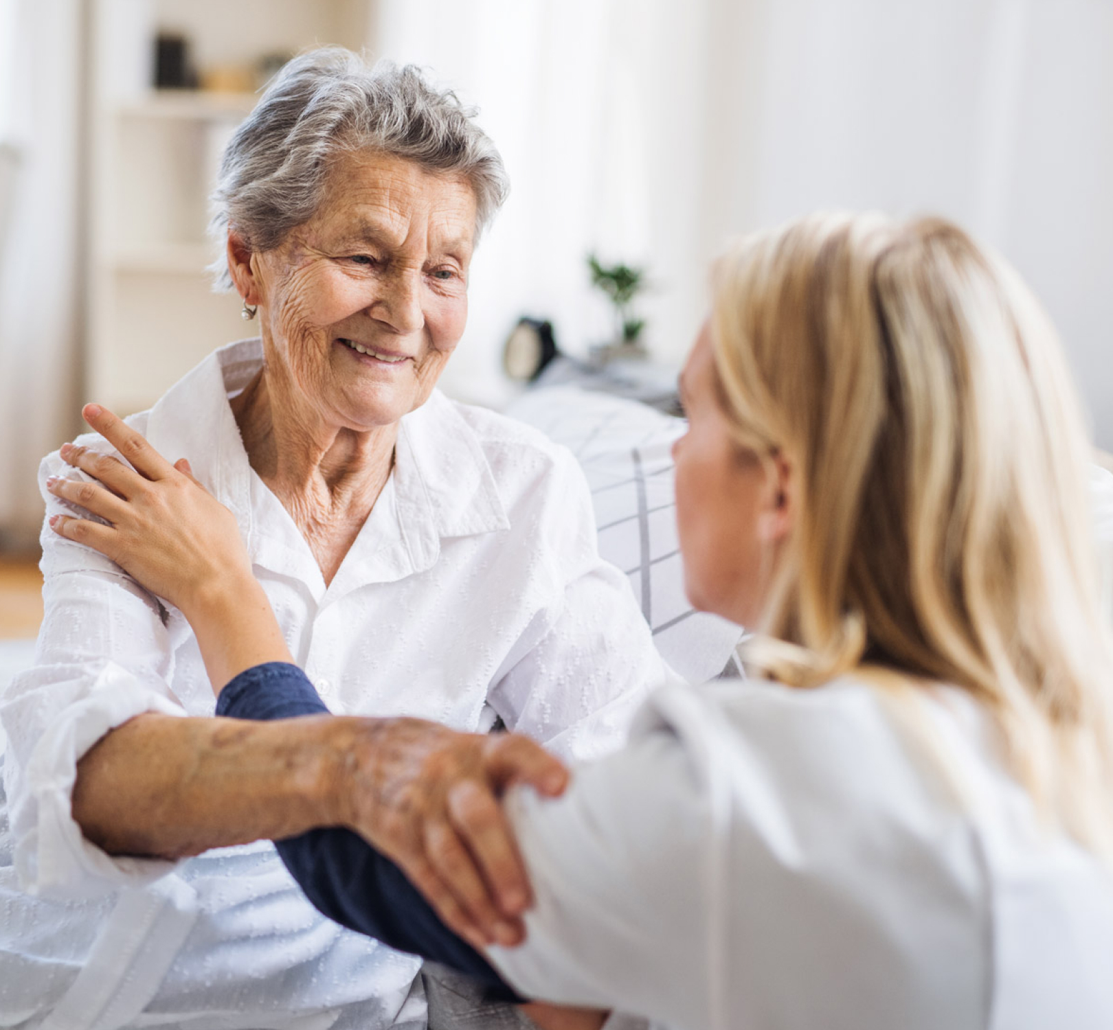 Caregiver comforting smiling elderly woman at home