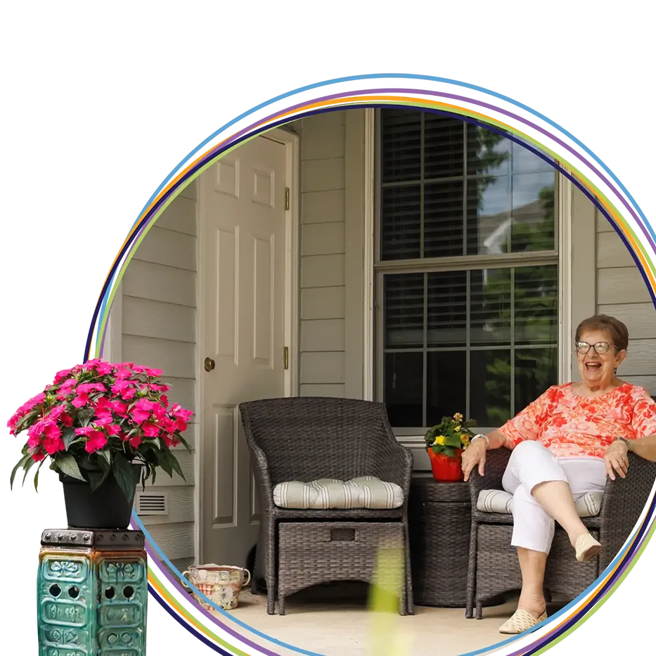 Smiling elderly woman sitting on porch with flowers