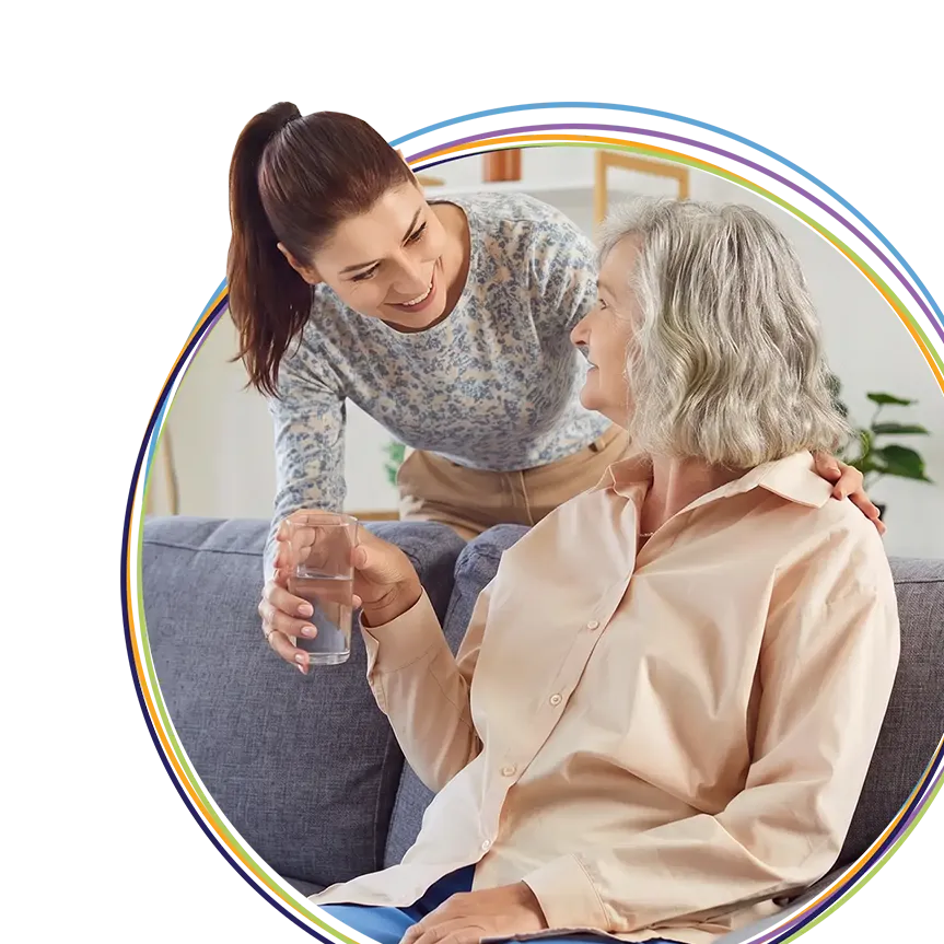 Caregiver giving elderly woman a glass of water