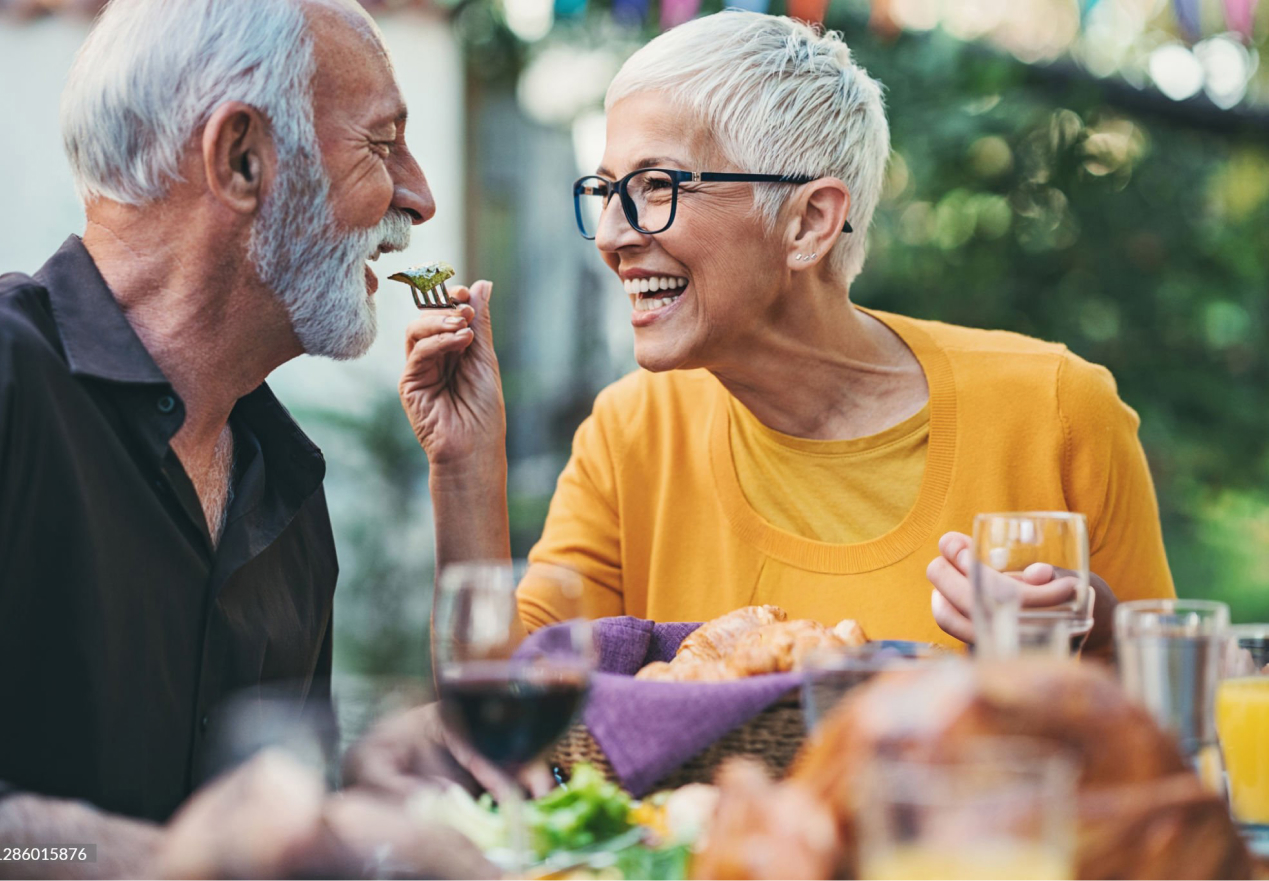 Senior couple laughing while sharing meal outdoors