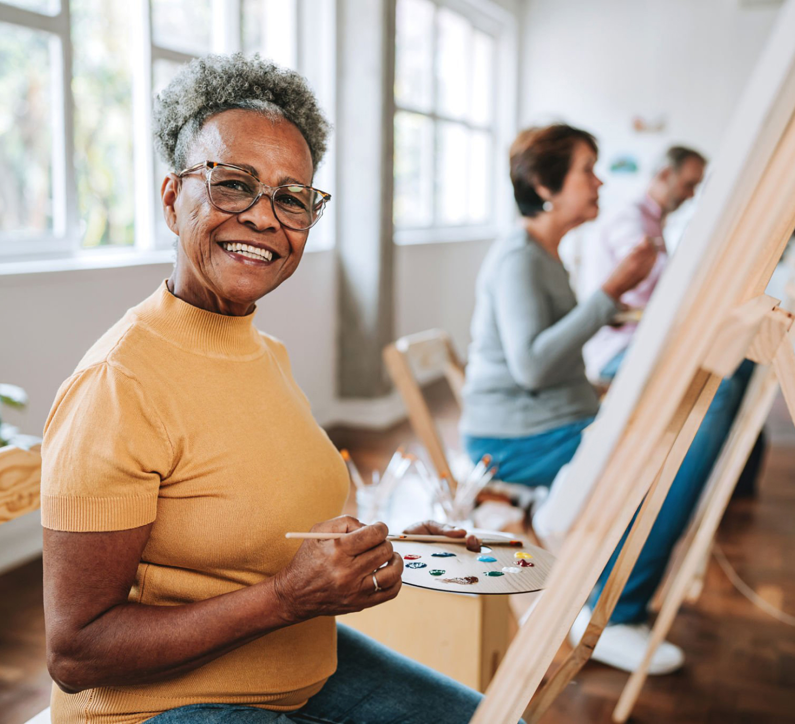 Smiling woman painting at easel in art class