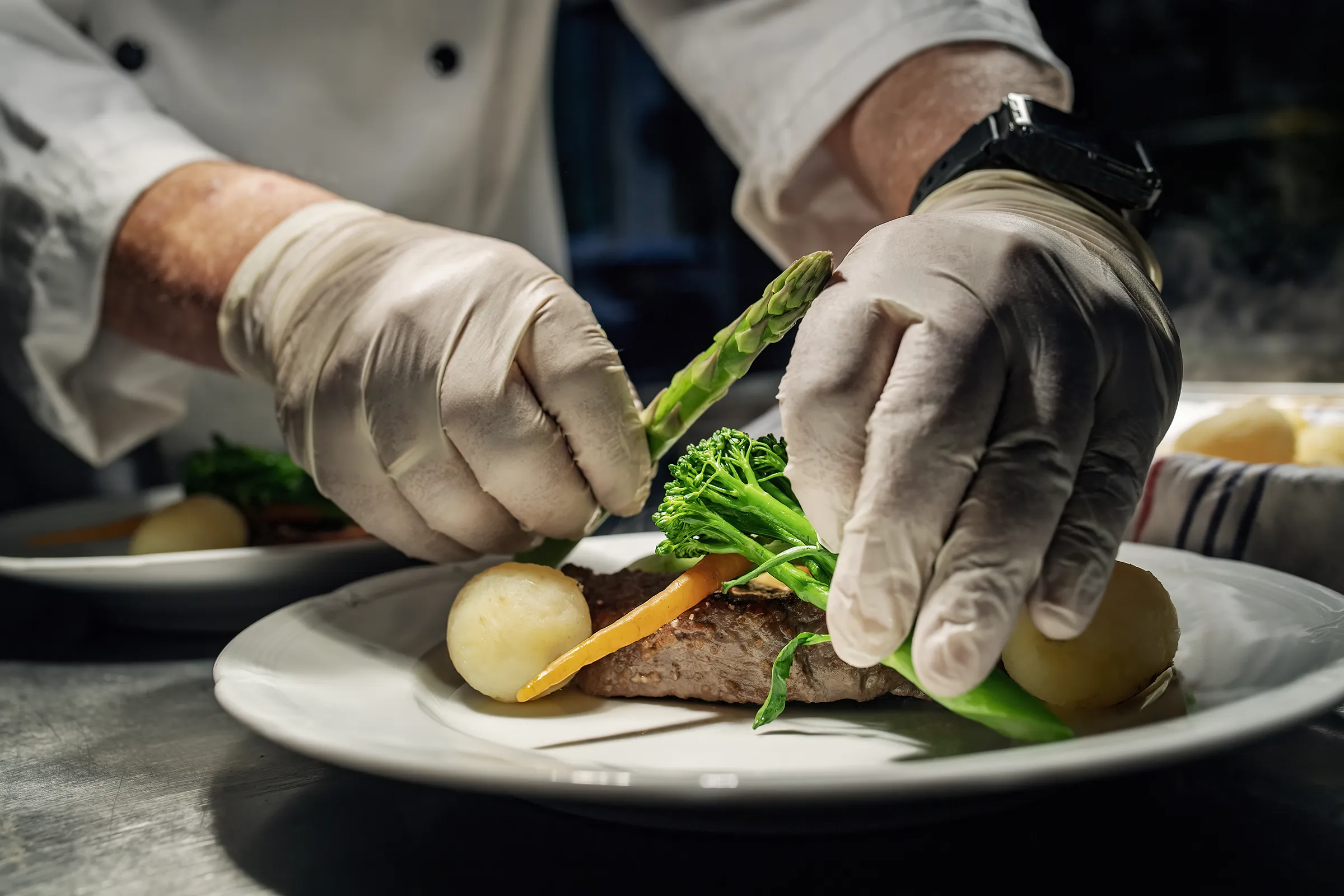 Chef plating steak with fresh vegetables