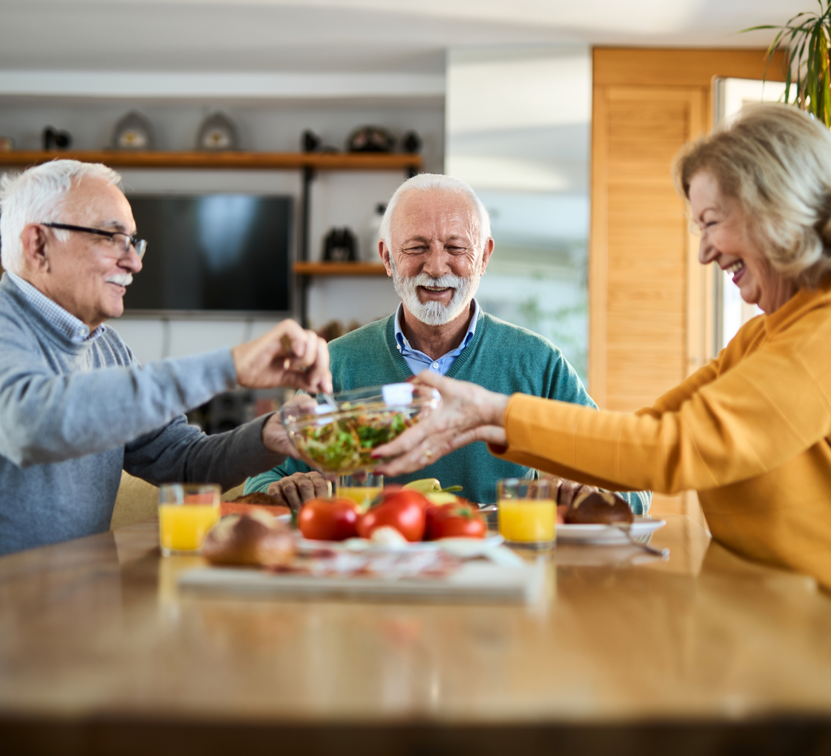 Three seniors sharing salad at dining table