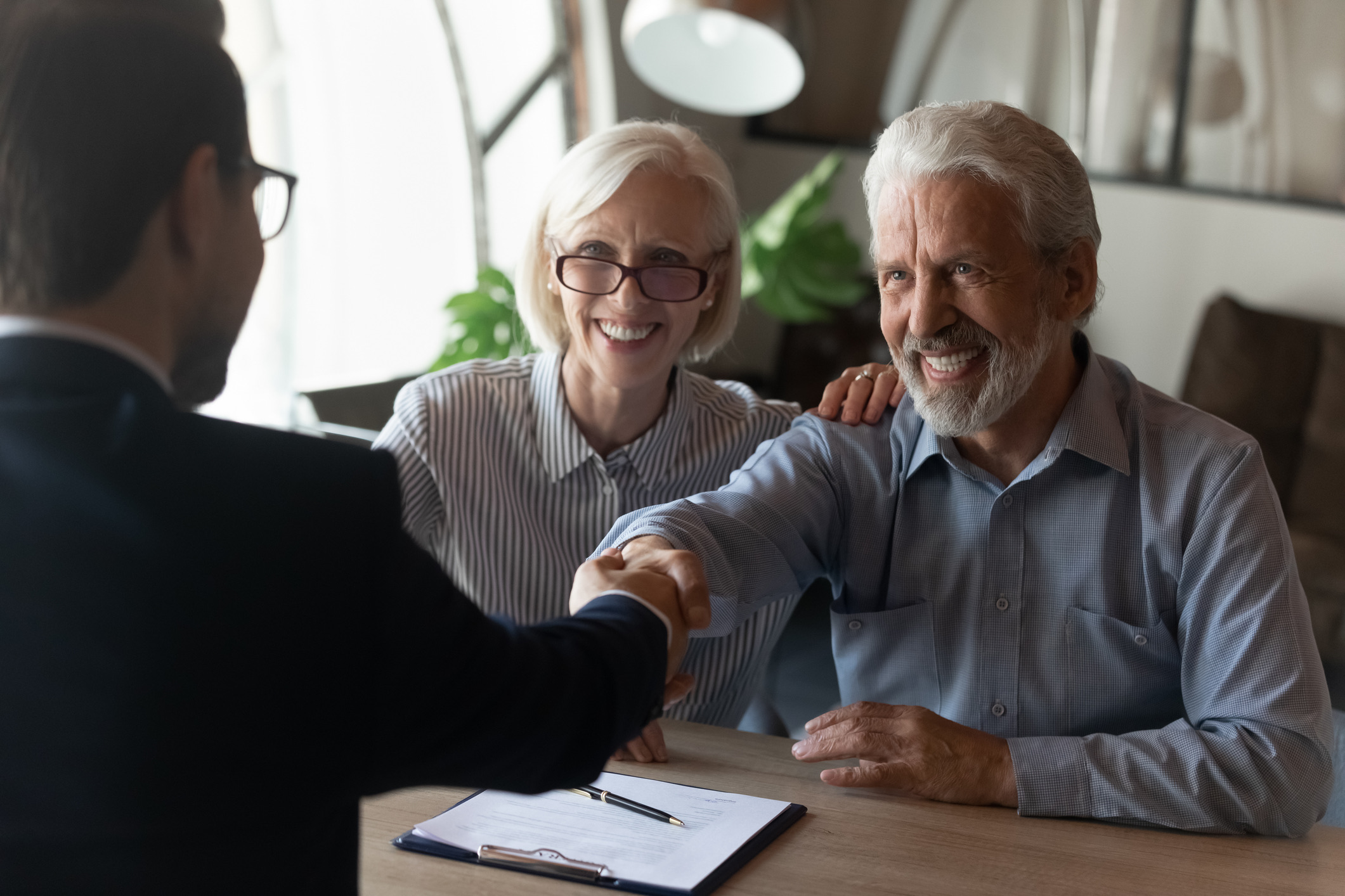 Senior couple shaking hands with financial advisor