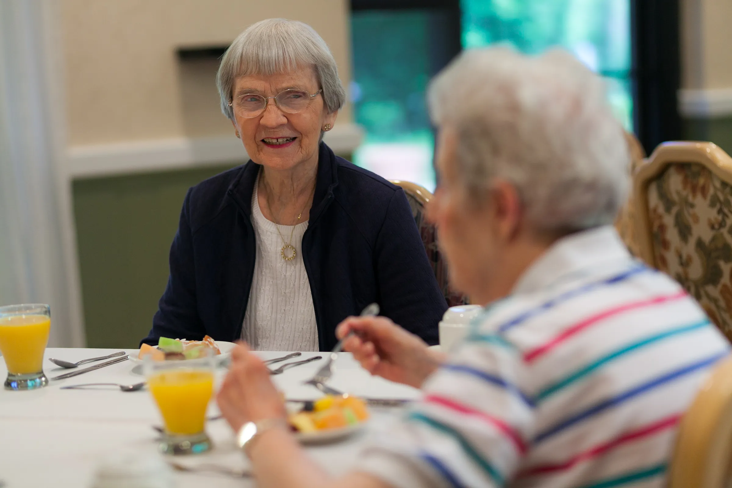Two elderly women sharing breakfast and conversation