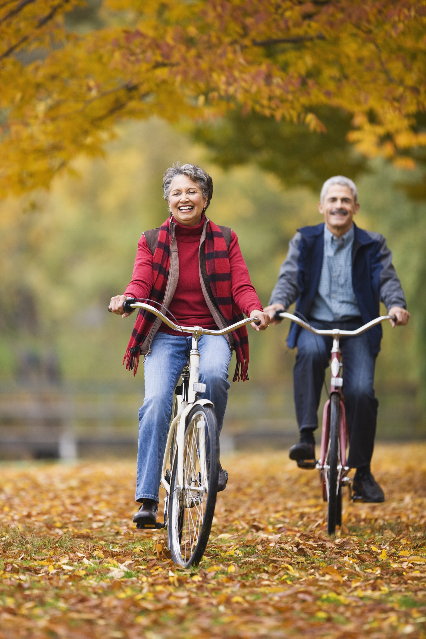 Senior couple riding bicycles in autumn park