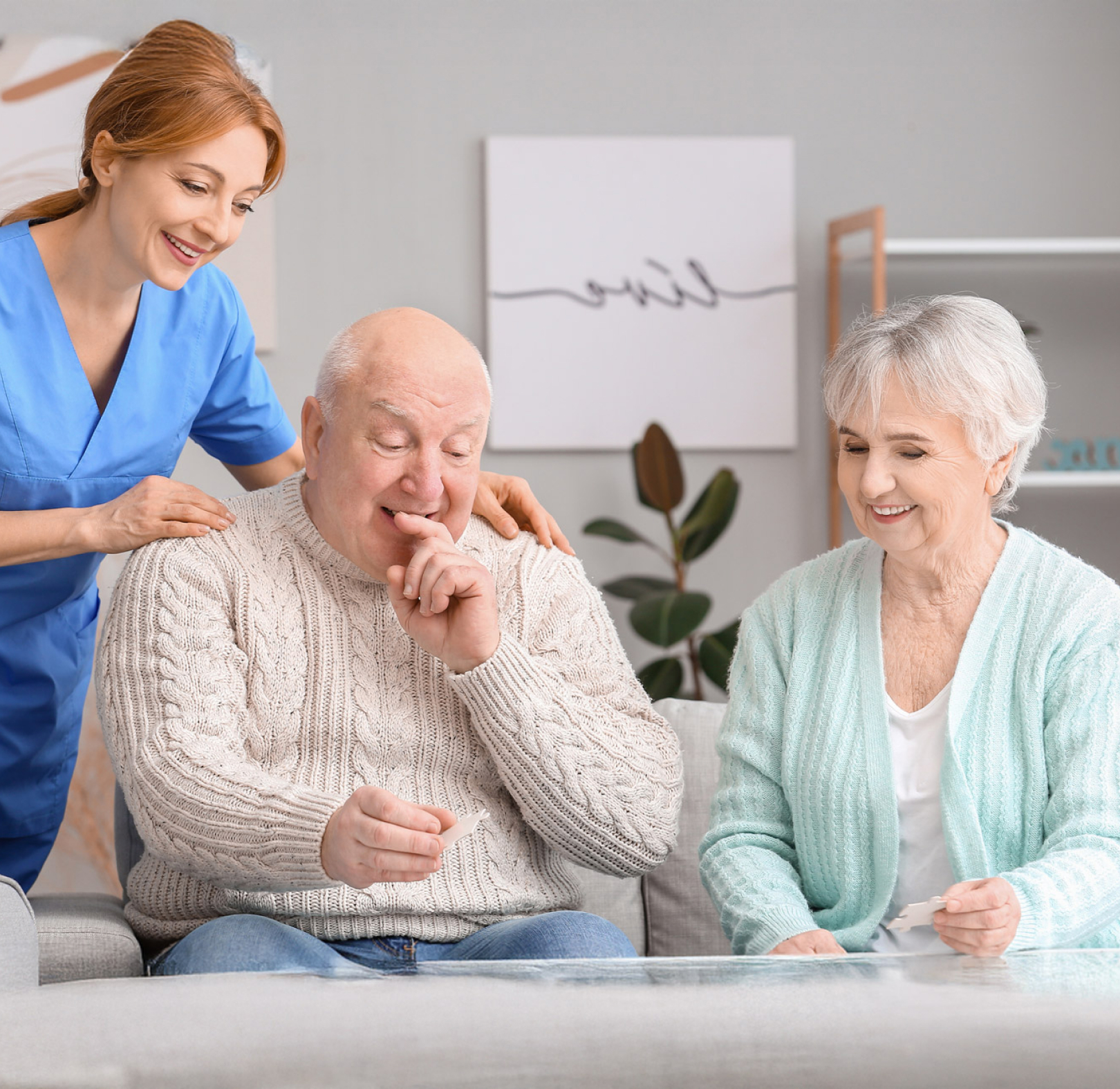 Caregiver with smiling elderly couple reviewing photos