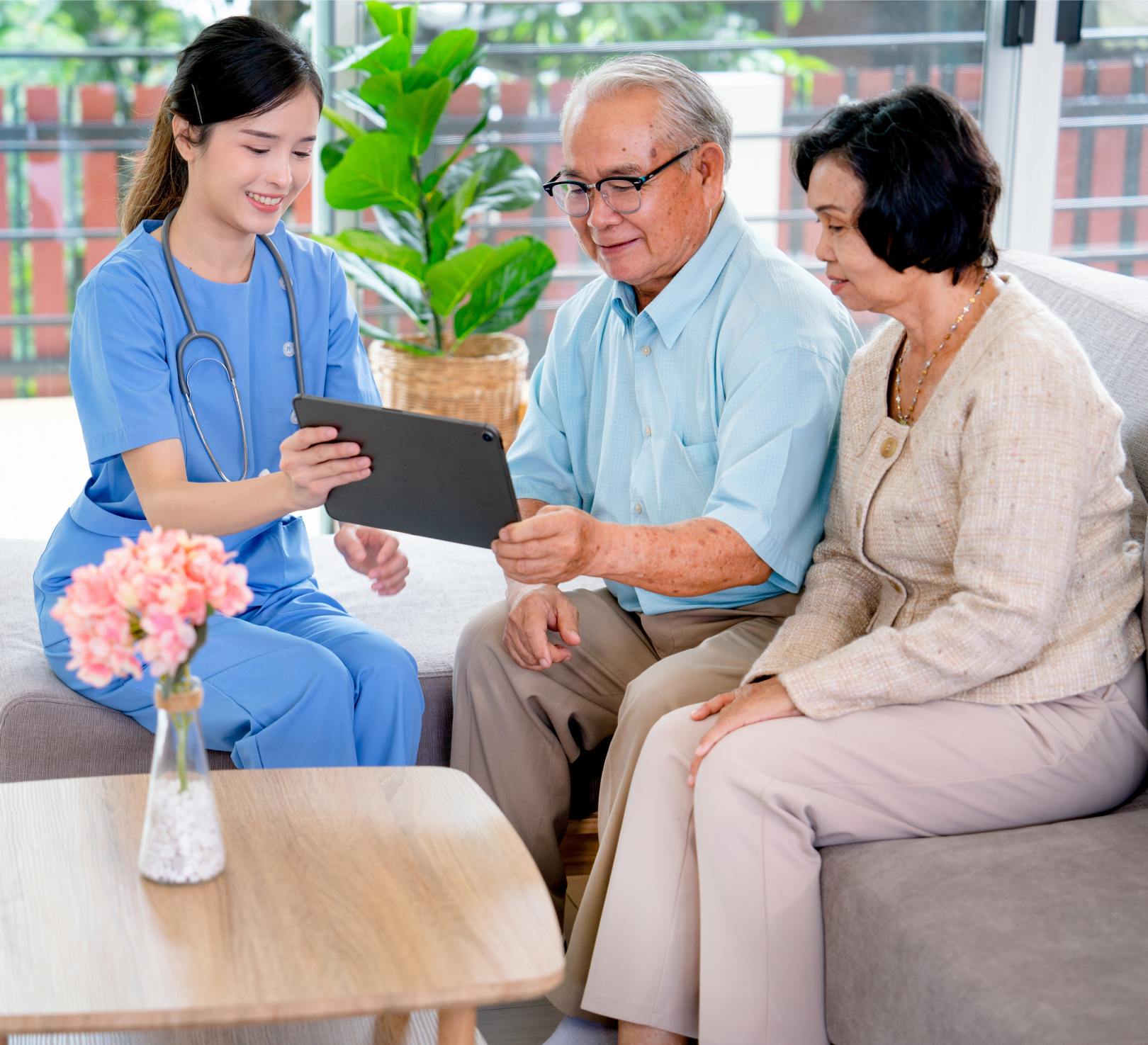 Nurse showing tablet to elderly couple at home