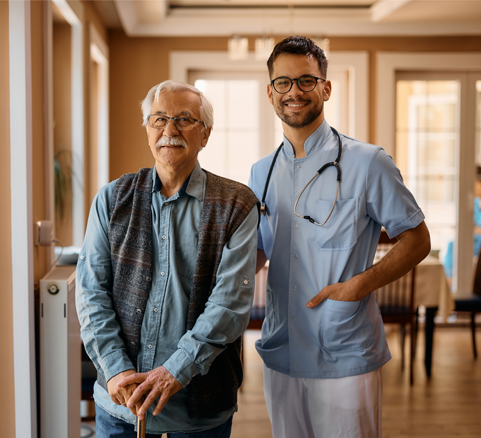 Elderly man and healthcare worker smiling indoors
