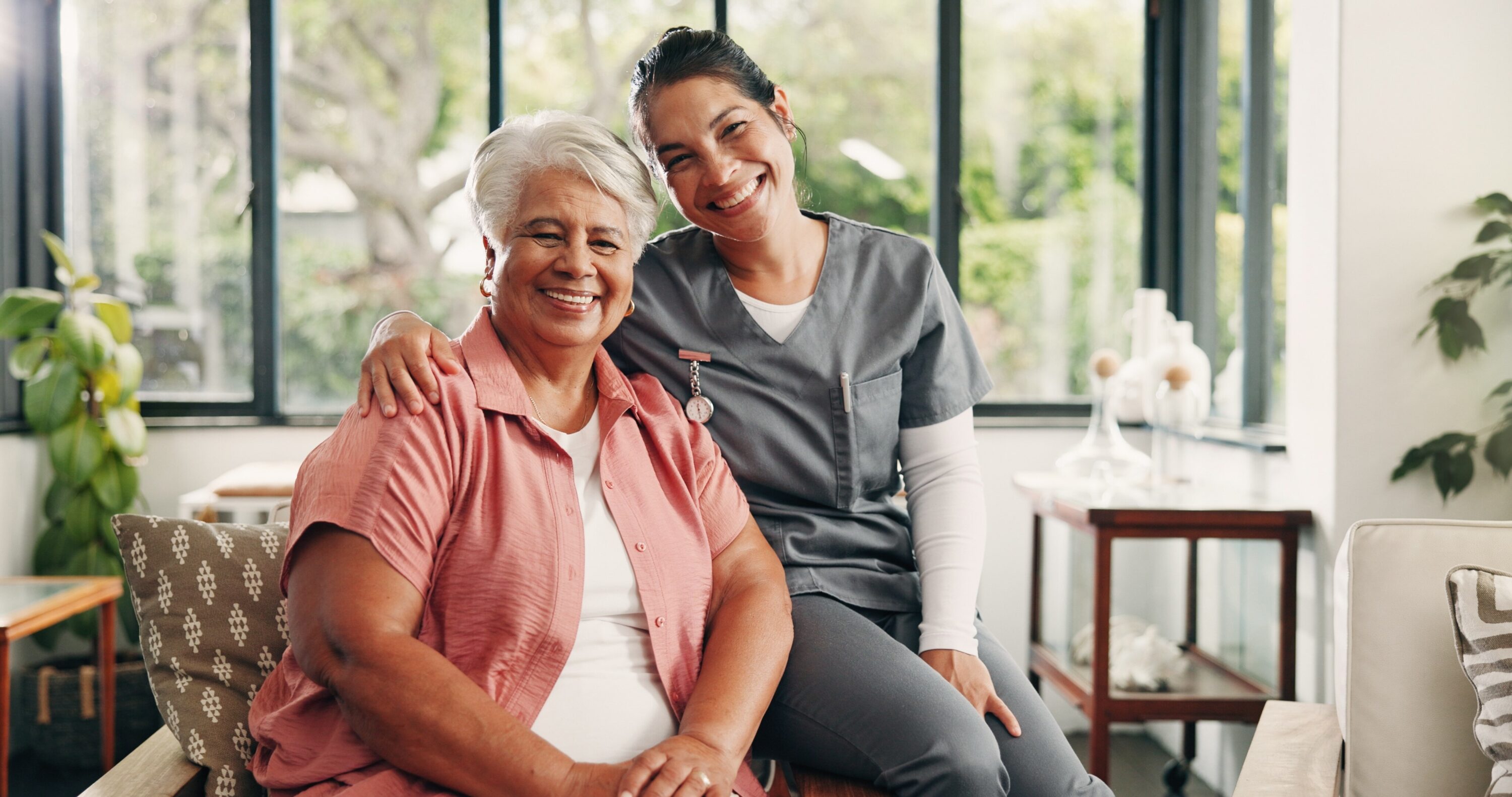 Caregiver and senior woman smiling together indoors