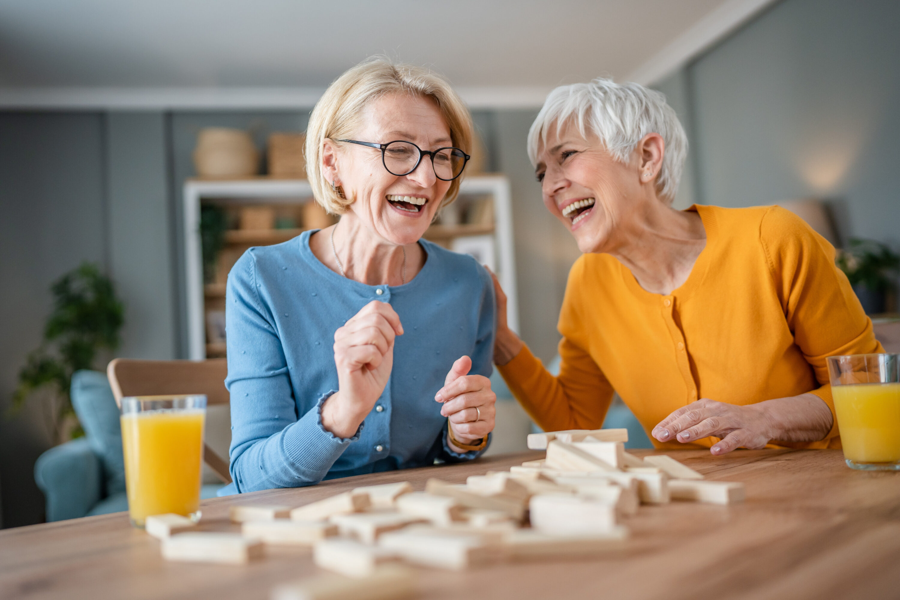 Two older women laughing while playing wooden block game
