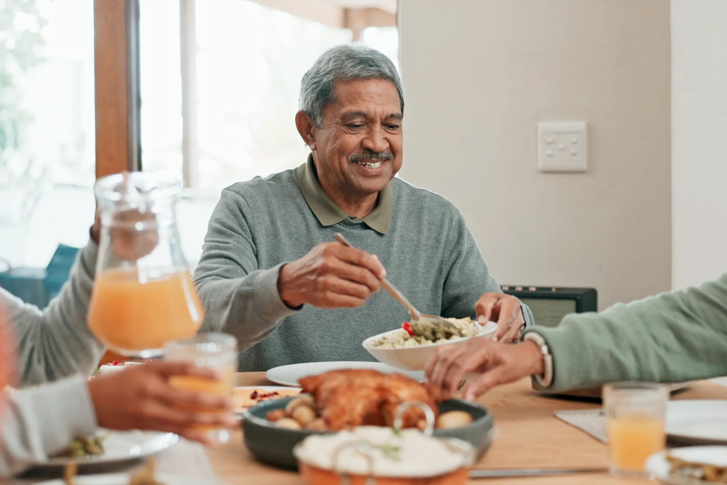 Smiling man serving food at family dinner table