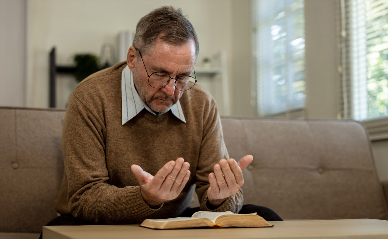 Man praying over open Bible at home