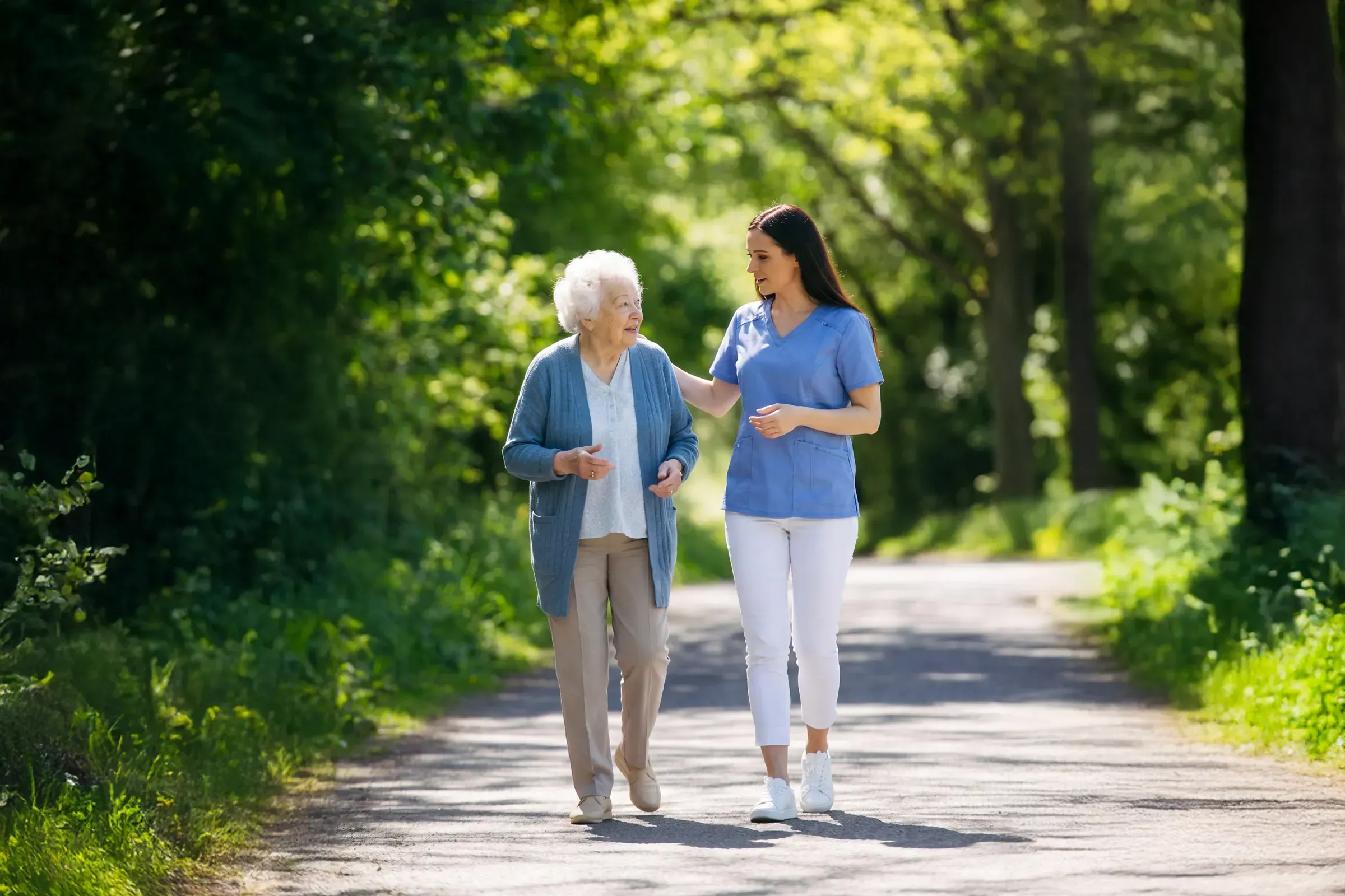 Caregiver walking with elderly woman in park
