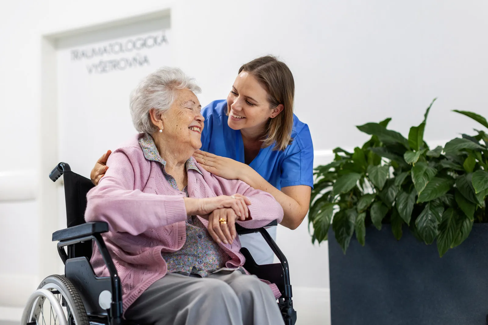 Nurse comforting elderly woman in wheelchair