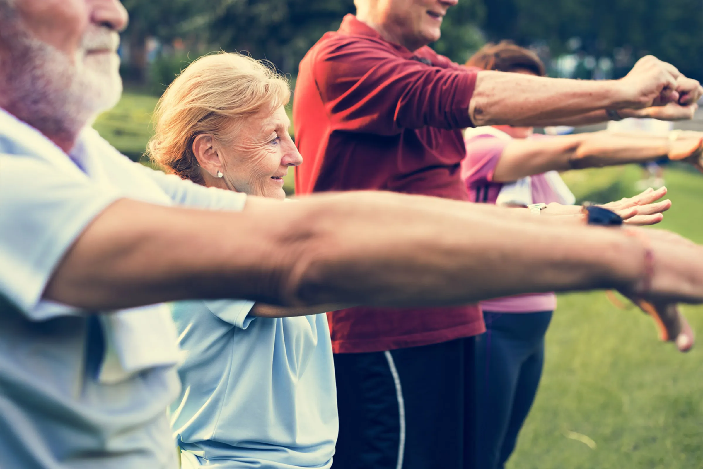 Seniors exercising together outdoors in a park