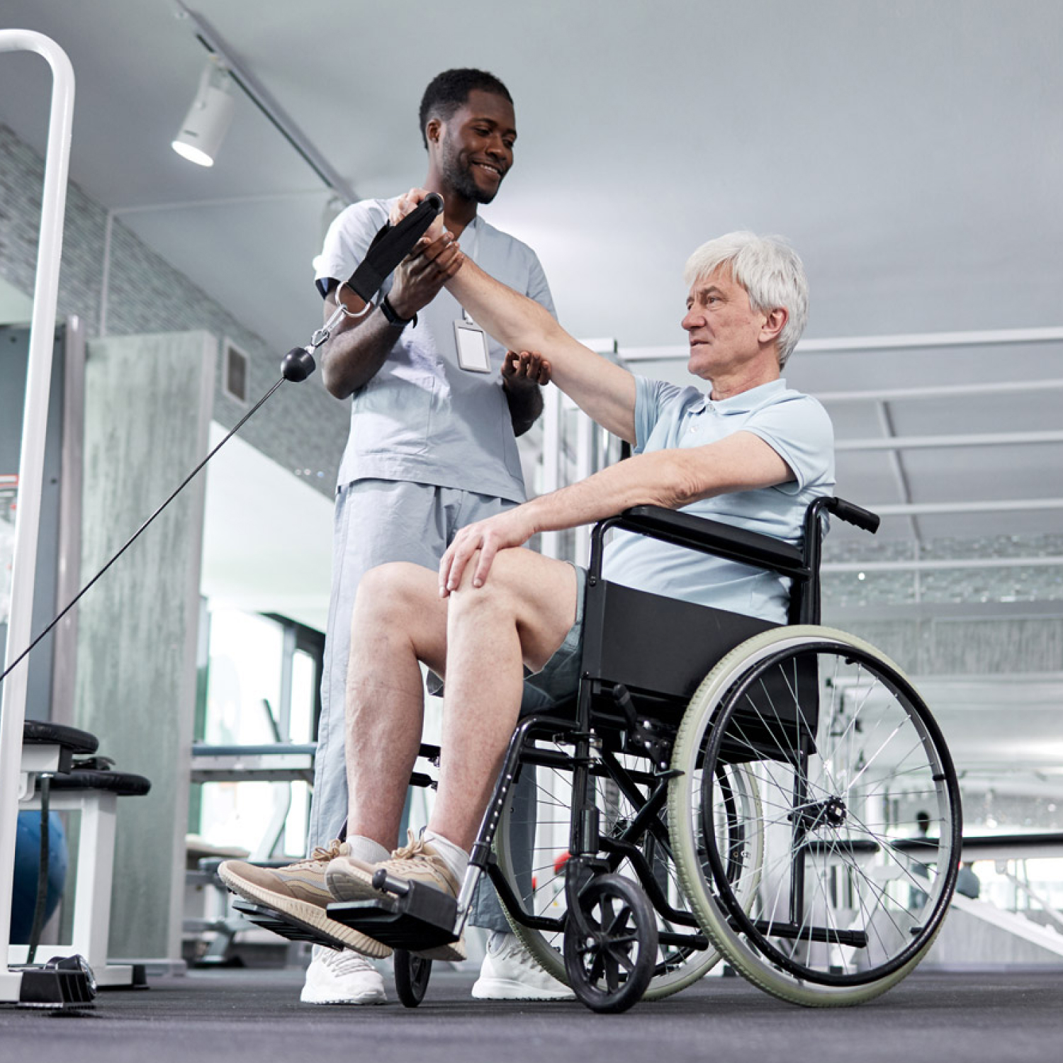 Physical therapist assisting senior in wheelchair exercise