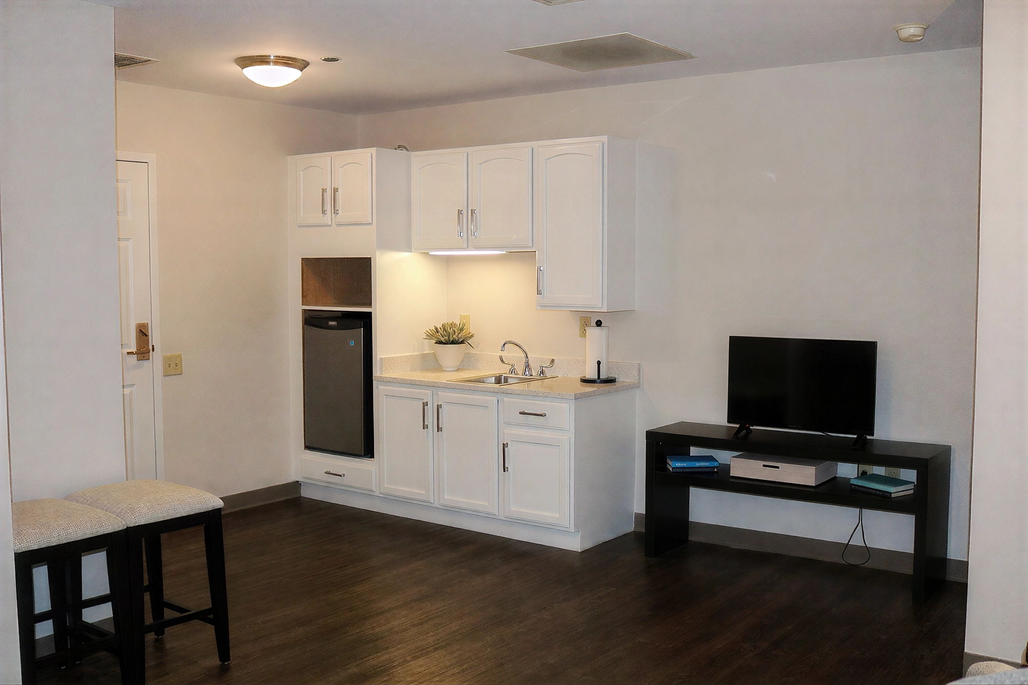 Small kitchenette with white cabinets and TV stand