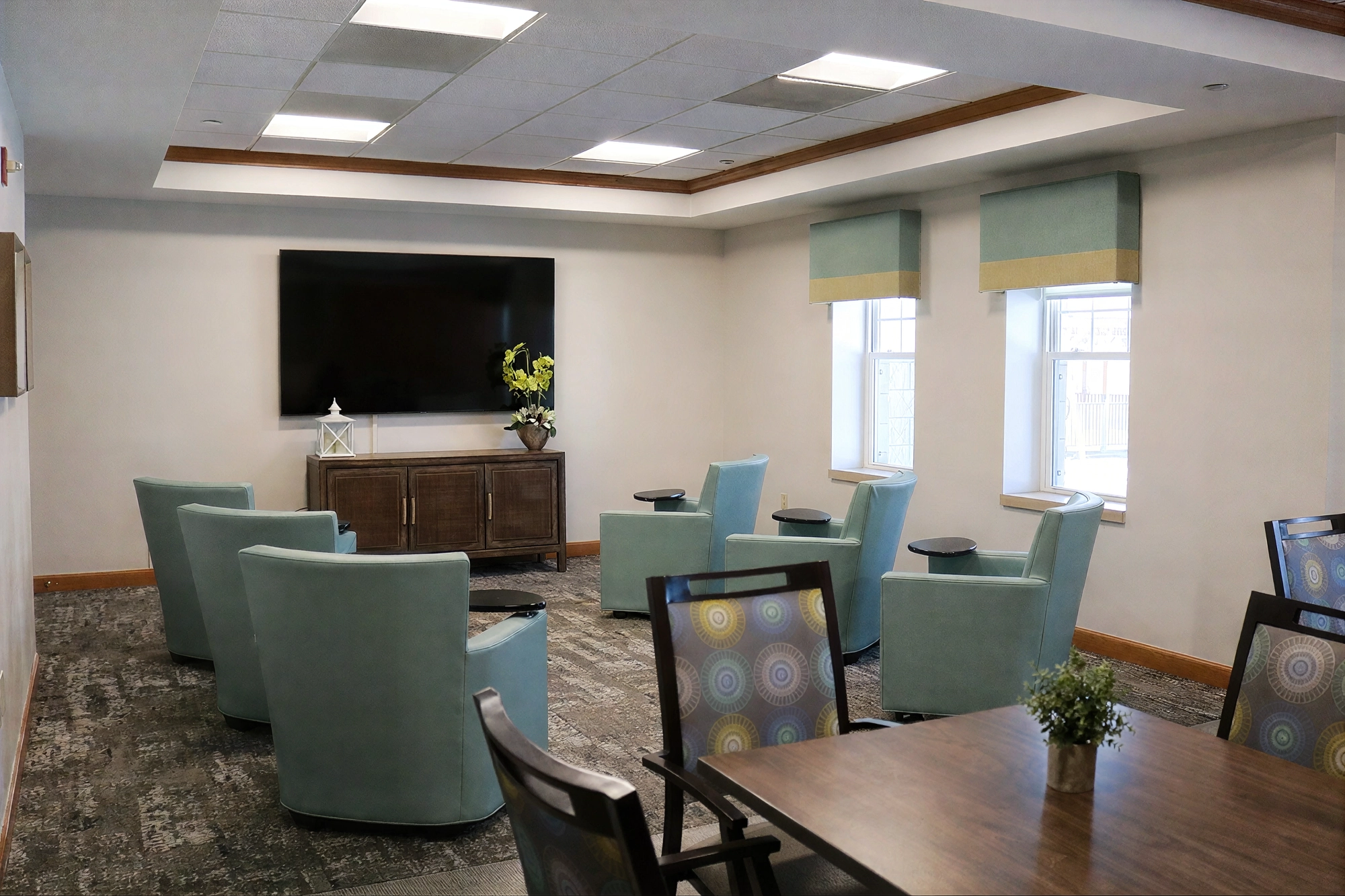 Modern lounge with teal chairs and wall-mounted TV